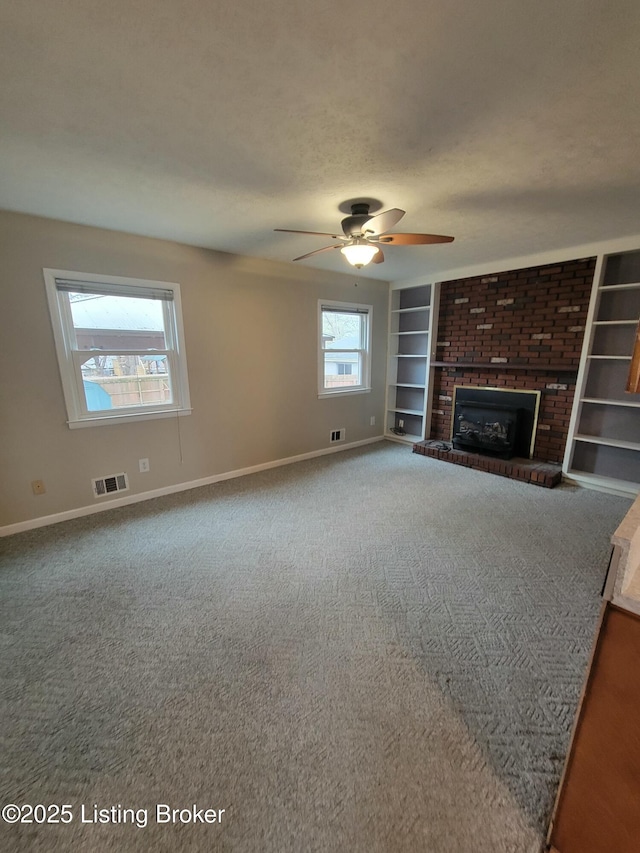 unfurnished living room featuring baseboards, visible vents, built in features, a textured ceiling, and a brick fireplace