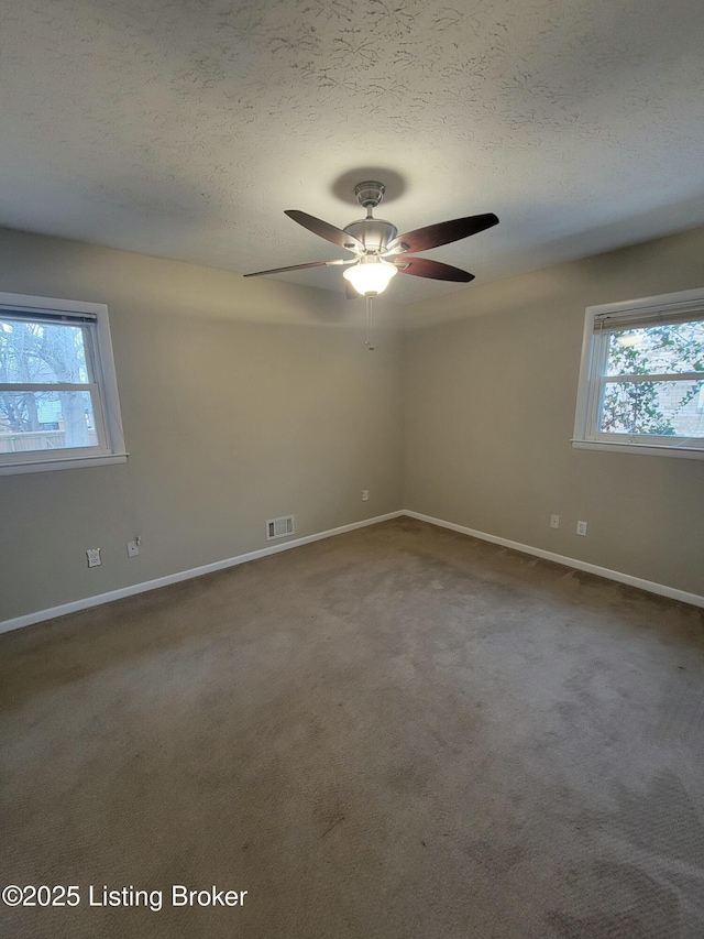 empty room with a textured ceiling, carpet floors, visible vents, and baseboards