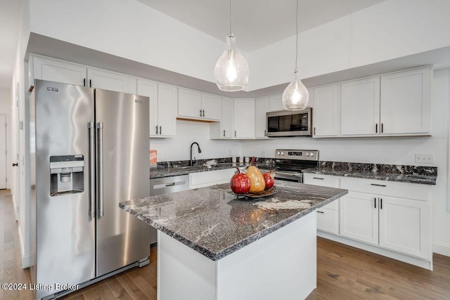 kitchen with white cabinetry, wood-type flooring, a kitchen island, pendant lighting, and stainless steel appliances