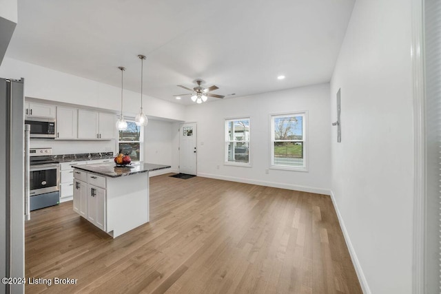 kitchen featuring stainless steel appliances, a center island, pendant lighting, and white cabinetry