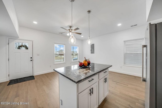 kitchen with a kitchen island, white cabinets, dark stone counters, ceiling fan, and light hardwood / wood-style flooring