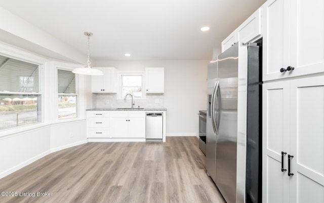 kitchen featuring pendant lighting, sink, white cabinetry, backsplash, and stainless steel appliances