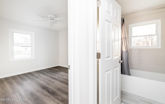 interior space featuring shower / bath combination with curtain, ceiling fan, and hardwood / wood-style floors