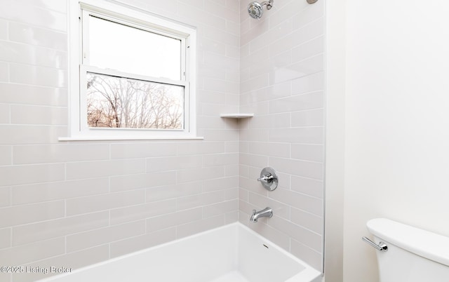 bathroom with tiled shower / bath combo and toilet