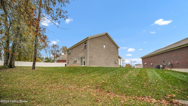 rear view of house featuring central AC unit and a lawn