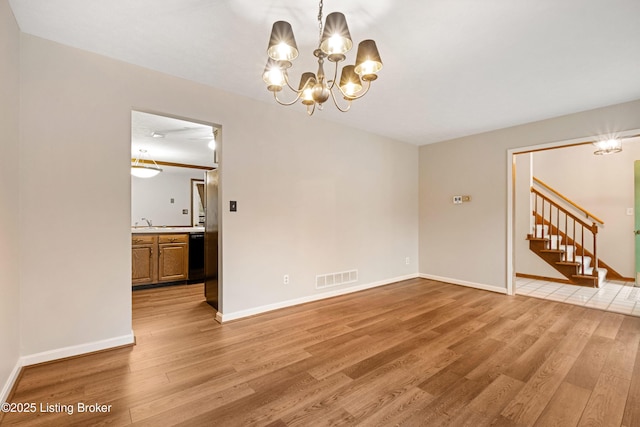 empty room with a chandelier and light hardwood / wood-style floors