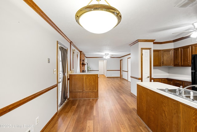 kitchen with wood-type flooring, ceiling fan, kitchen peninsula, crown molding, and black fridge