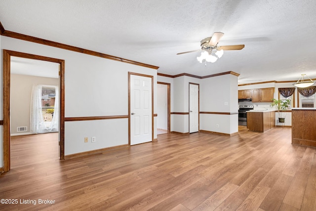 unfurnished living room featuring ornamental molding, ceiling fan, a textured ceiling, and light hardwood / wood-style flooring