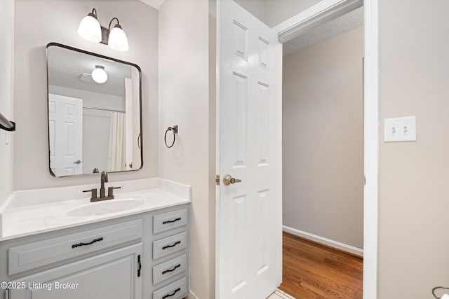 bathroom featuring vanity, wood-type flooring, a textured ceiling, and walk in shower