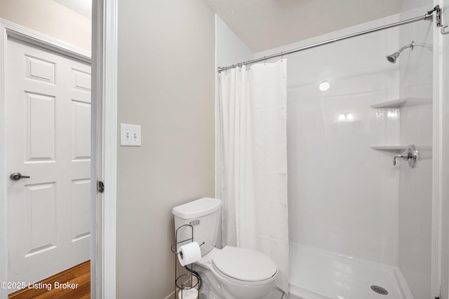 bathroom featuring toilet and a shower with shower curtain