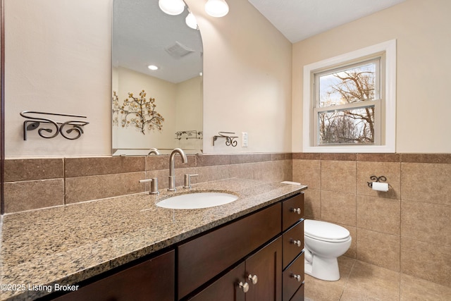 bathroom featuring vanity, tile patterned floors, tile walls, and toilet