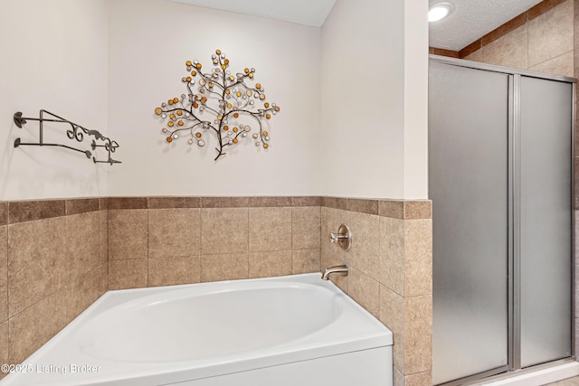 bathroom with shower with separate bathtub and a textured ceiling