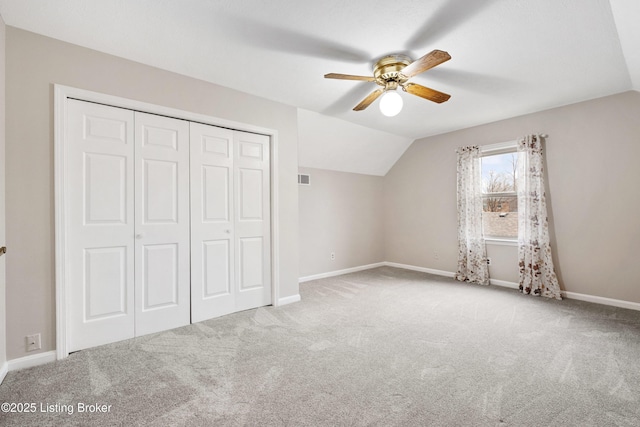 unfurnished bedroom with ceiling fan, a closet, lofted ceiling, and light carpet