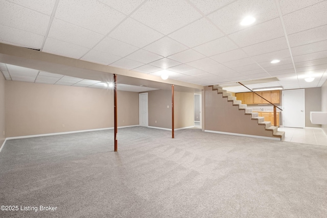 basement featuring a paneled ceiling and carpet flooring