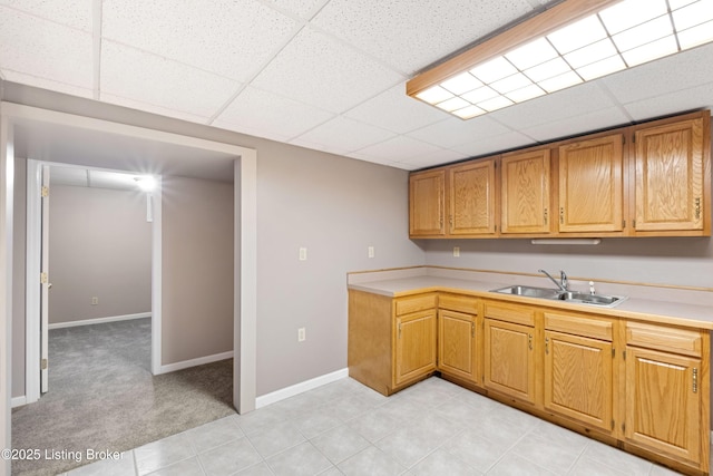 kitchen featuring light colored carpet, sink, and a drop ceiling