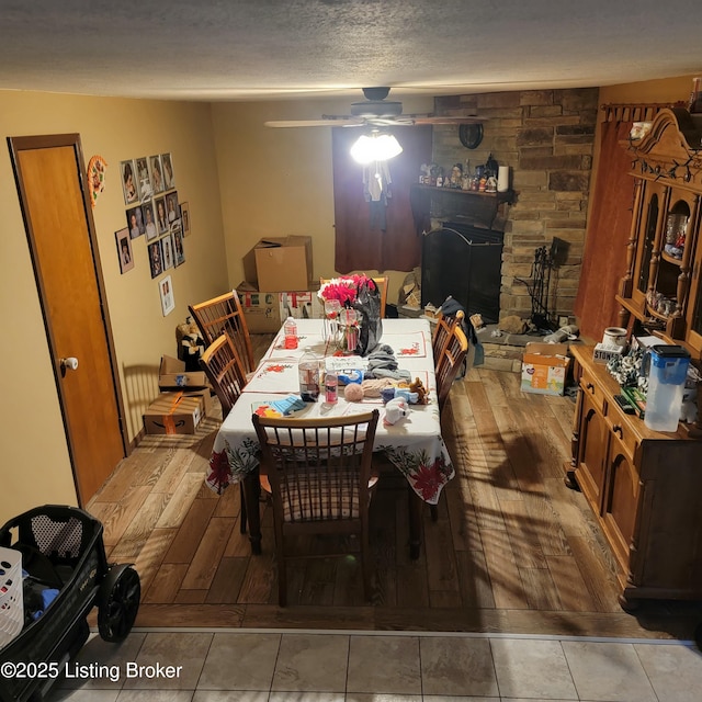 dining area with ceiling fan, hardwood / wood-style floors, a textured ceiling, and a fireplace