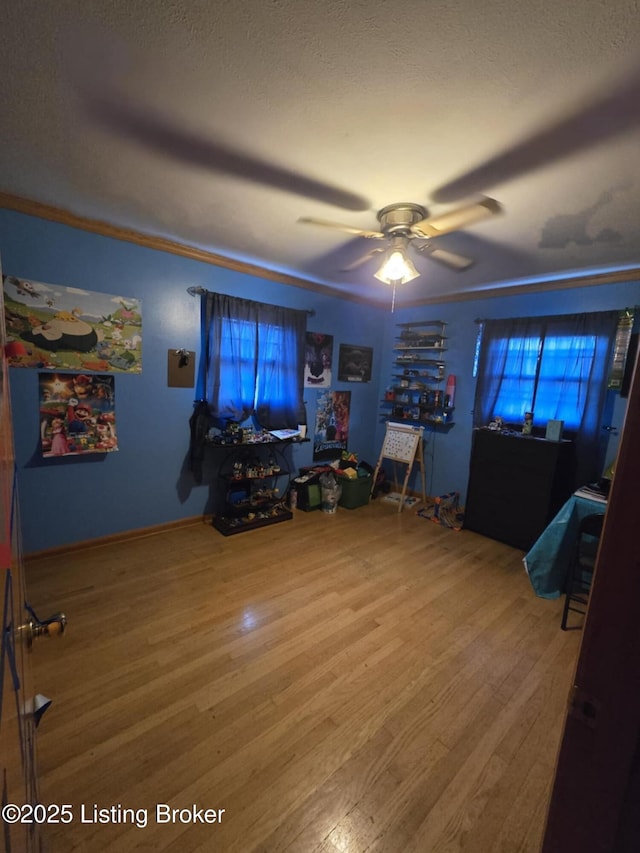 interior space featuring ceiling fan, hardwood / wood-style flooring, ornamental molding, and a textured ceiling