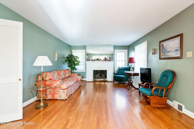 living room with hardwood / wood-style flooring and a brick fireplace