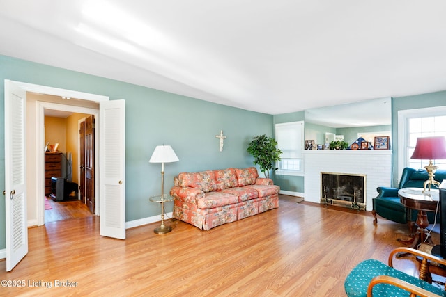 living room with a brick fireplace and light wood-type flooring