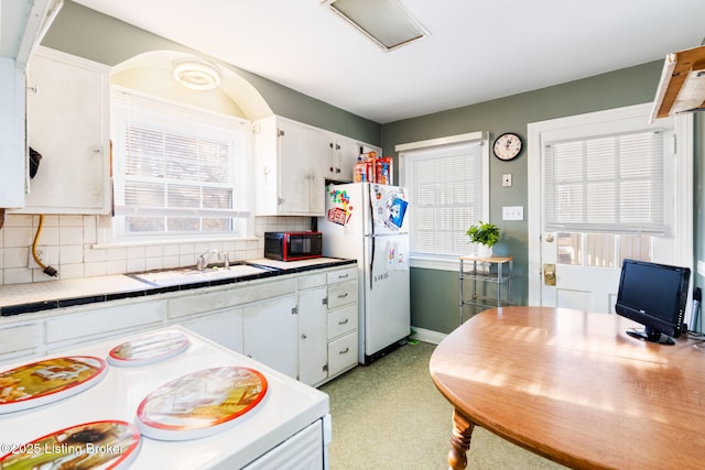 kitchen featuring white cabinetry, sink, backsplash, tile counters, and white appliances