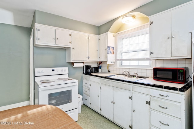 kitchen with white range with electric stovetop, tasteful backsplash, sink, white cabinets, and tile counters