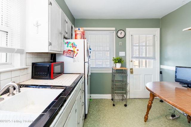 kitchen featuring white cabinetry, white refrigerator, sink, and tasteful backsplash