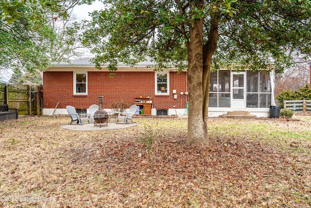 rear view of property with a sunroom and an outdoor fire pit