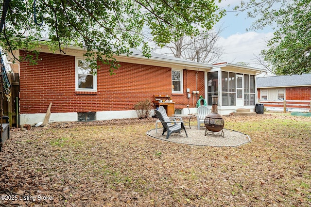 back of house with a sunroom and an outdoor fire pit