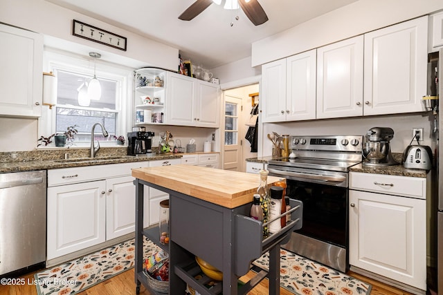 kitchen featuring sink, light hardwood / wood-style flooring, appliances with stainless steel finishes, dark stone countertops, and white cabinets