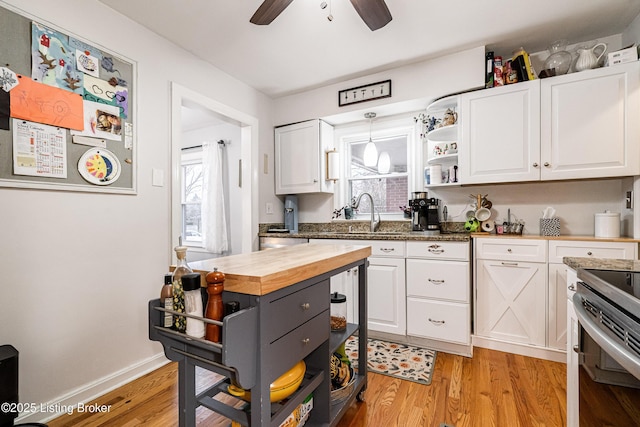 kitchen featuring sink, wooden counters, white cabinetry, decorative light fixtures, and light wood-type flooring