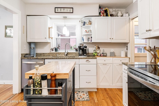 kitchen with hanging light fixtures, sink, wooden counters, and white cabinets