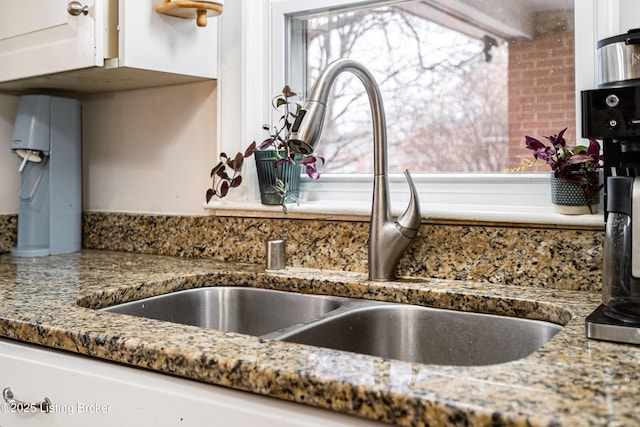 interior details with white cabinetry, sink, and dark stone countertops