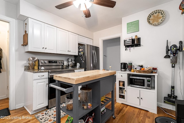 kitchen with butcher block countertops, white cabinetry, light wood-type flooring, ceiling fan, and stainless steel appliances