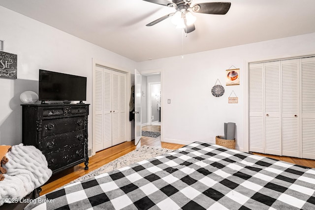 bedroom featuring ceiling fan, light hardwood / wood-style floors, and two closets