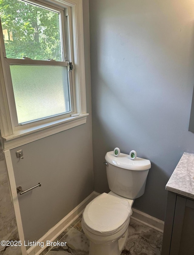 half bathroom featuring baseboards, vanity, and toilet