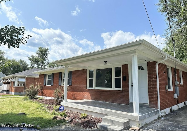 single story home with a porch, a front yard, and brick siding