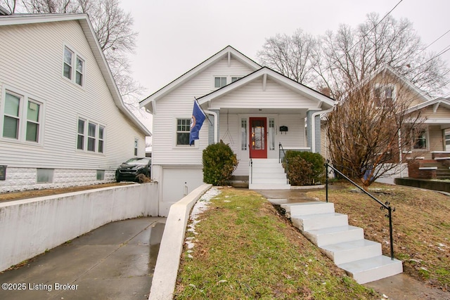 bungalow-style house featuring a garage, a porch, and a front lawn