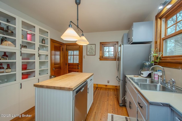 kitchen featuring decorative light fixtures, a center island, white cabinets, and appliances with stainless steel finishes