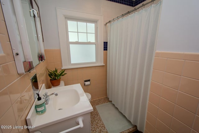 bathroom with vanity, toilet, curtained shower, and tile walls