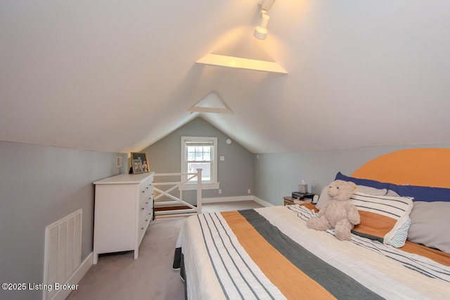 carpeted bedroom with vaulted ceiling and track lighting