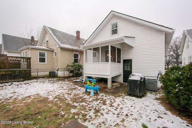 snow covered property with a sunroom and central AC unit