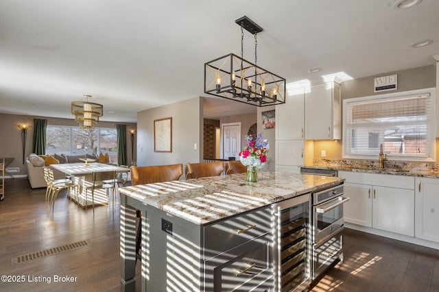 kitchen with white cabinetry, sink, and light stone countertops