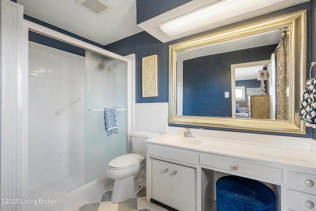 bathroom featuring a shower with shower door, tile walls, vanity, toilet, and tile patterned floors