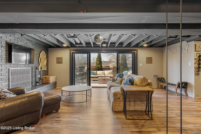 living room with beamed ceiling, a brick fireplace, and hardwood / wood-style floors