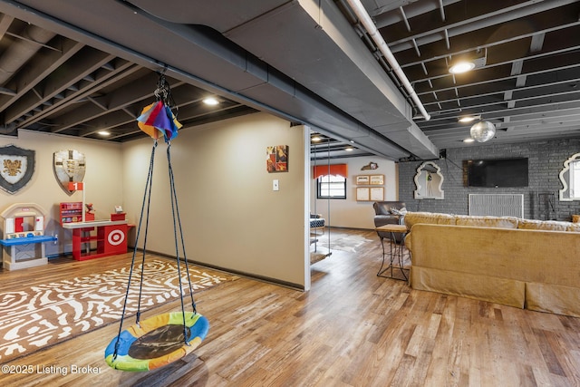 playroom featuring wood-type flooring and brick wall