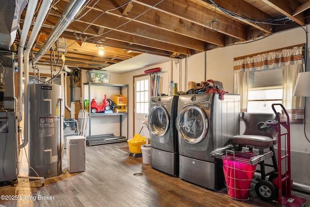 clothes washing area featuring wood-type flooring, washer and clothes dryer, and water heater