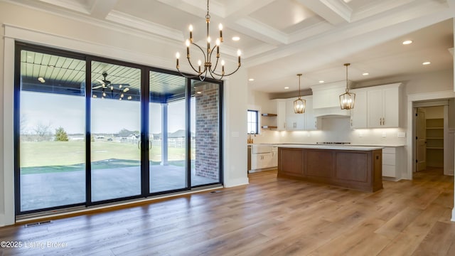 kitchen featuring decorative light fixtures, white cabinets, a large island, light hardwood / wood-style floors, and backsplash