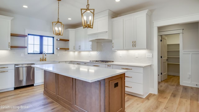 kitchen featuring sink, white cabinetry, a center island, appliances with stainless steel finishes, and pendant lighting