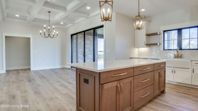 kitchen featuring pendant lighting, sink, backsplash, and white cabinets