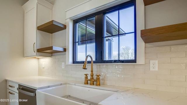 kitchen with sink, dishwasher, tasteful backsplash, light stone counters, and white cabinets